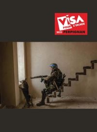 Daniel Berehurlak's photo of a soldier of the armed forces patrolling the territory in liberated Irpen with a dog, VISA POUR L'IMAGE 2022, in white font to red banner above.