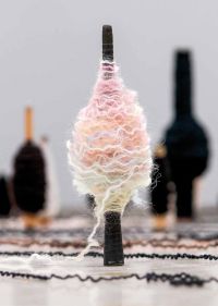 Book cover of Kari Steihaug, with a spinning spool bound with wavy wool in pastel colours. Published by Arnoldsche Art Publishers.