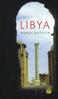 Dark archway in a Libyan city with tall column standing in the light, 'LIBYA', in red font above.