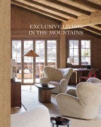 Book cover of Exclusive Living in the Mountains, with interior of wood chalet with cream sofa, and view over mountains. Published by Beta-Plus.