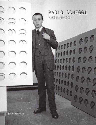 Paolo Scheggi in suit, standing in a studio surrounded by his elliptical holed canvases, on cover of a monography, by Silvana.