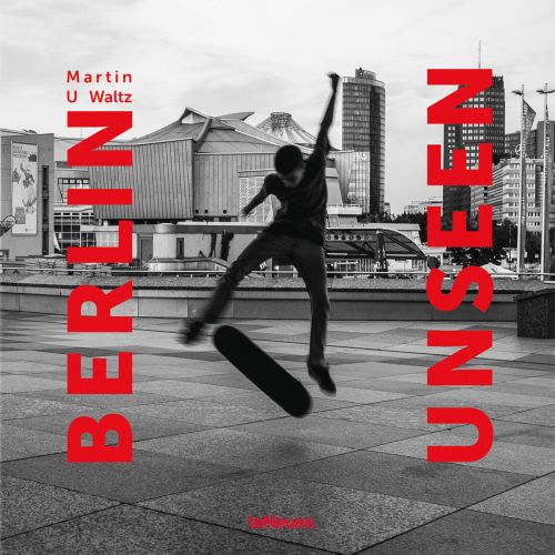 Young white male skateboarder performing a trick in the air, city architecture behind, on cover of 'BERLIN UNSEEN', by teNeues Books.