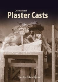 Duel-headed white plaster cast with sculptor underneath, on cover of 'Conservation of Plaster Casts', by Archetype Publications.