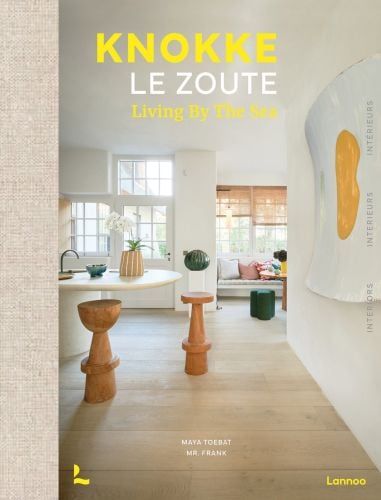 Book cover of Knokke Le Zoute Interiors, Living by the Sea, with white, open-plan kitchen/living room interior with wood floors. Published by Lannoo Publishers.