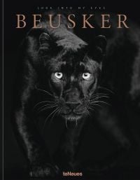 Black panther with silvery-grey eyes staring at the camera, on black cover of 'Beusker, Look into my Eyes', by teNeues Books.