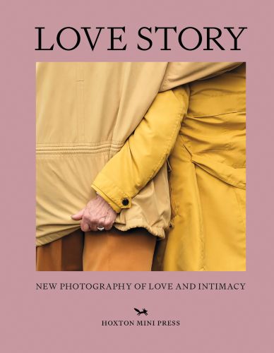 Rear of couple in mustard yellow coats, one clutching the bottom of the other's coat, on pink cover of 'Love Story, New Photography of Love and Intimacy', by Hoxton Mini Press.