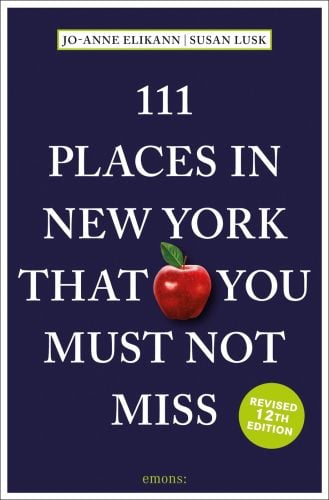 Red apple near centre of dark blue travel guide '111 Places in New York That You Must Not Miss', by Emons Verlag.