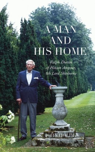 Man in blue jacket, holding walking stick while leaning on concrete sundial in garden lined with conifer trees, on cover of 'Ralph Dutton of Hinton Ampner, A Man and his Home', by Pallas Athene.