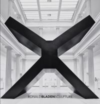 Large black minimalist sculpture in shape of an 'X', in exhibition space, on cover of 'Ronald Bladen, Sculpture', by Abbeville Press.