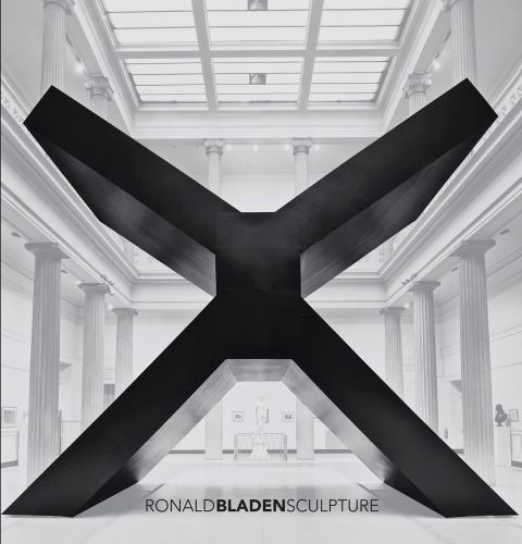 Large black minimalist sculpture in shape of an 'X', in exhibition space, on cover of 'Ronald Bladen, Sculpture', by Abbeville Press.