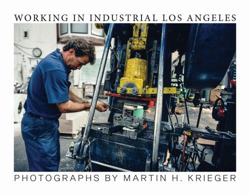 Man in blue shirt and trousers working on a large mechanical object, on landscape cover of 'Working in Industrial Los Angeles', by ORO Editions.