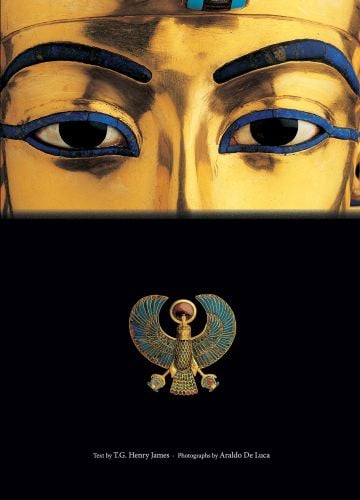 Close-up of the eyes of the golden statue of the Egyptian Pharaoh, Falcon Pectoral below, on black cover of 'Tutankhamun', by White Star.