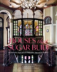 Grand interior with dark wood staircase, chandelier and stained glass interior windows, on cover of 'Houses that Sugar Built, An Intimate Portrait of Philippine Ancestral Homes', by ORO Editions.