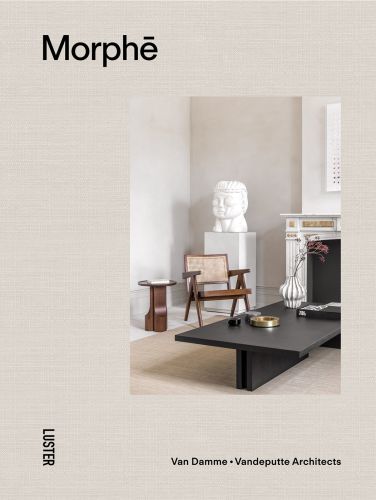Interior space with low black coffee-table, white bust sculpture on plinth, wood chair, white marble fireplace, on beige linen cover 'Morph?, Van Damme - Vandeputte Architects', by Luster Publishing.