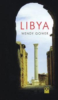 Dark archway in a Libyan city with tall column standing in the light, 'LIBYA', in red font above.