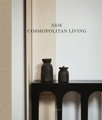 Book cover of New Cosmopolitan Living, with two dark vessels resting on wood surface, with white walls and wood corner panels behind. Published by Beta-Plus.