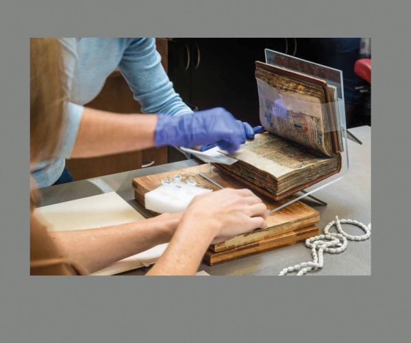 Group of people looking through large library books, on grey cover, Photographing Shakespeare in gold font below