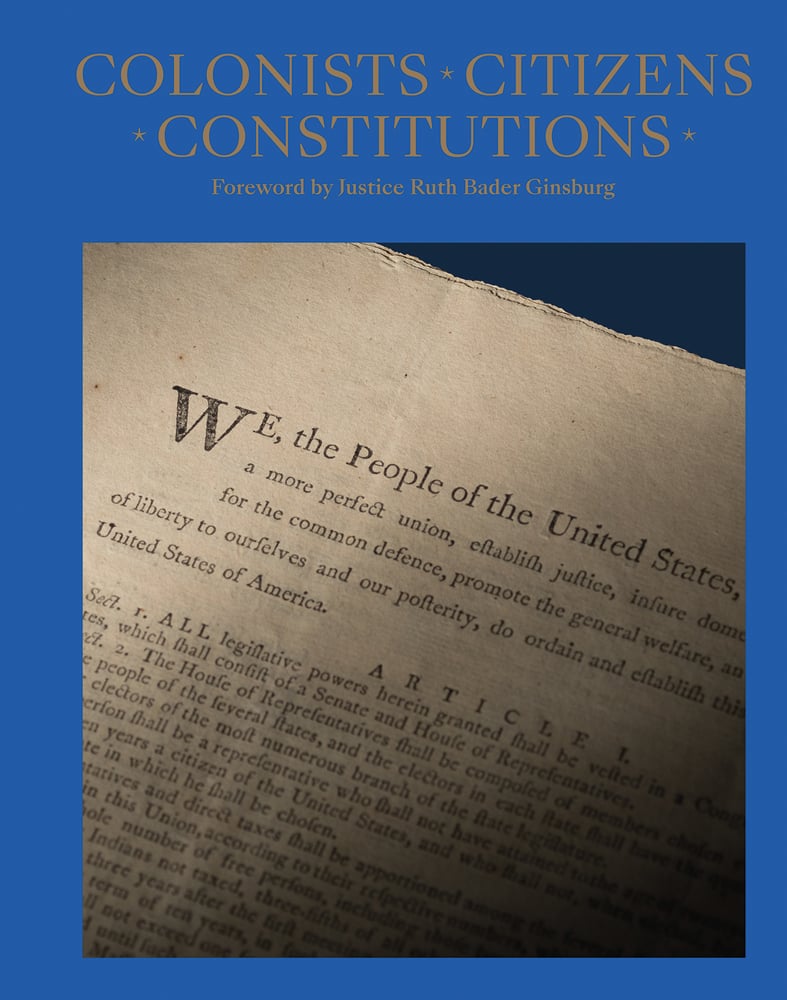 Yellowed newspaper document headed We the people of the United States, on blue cover, COLONISTS, CITIZENS, CONSTITUTIONS in gold font above.
