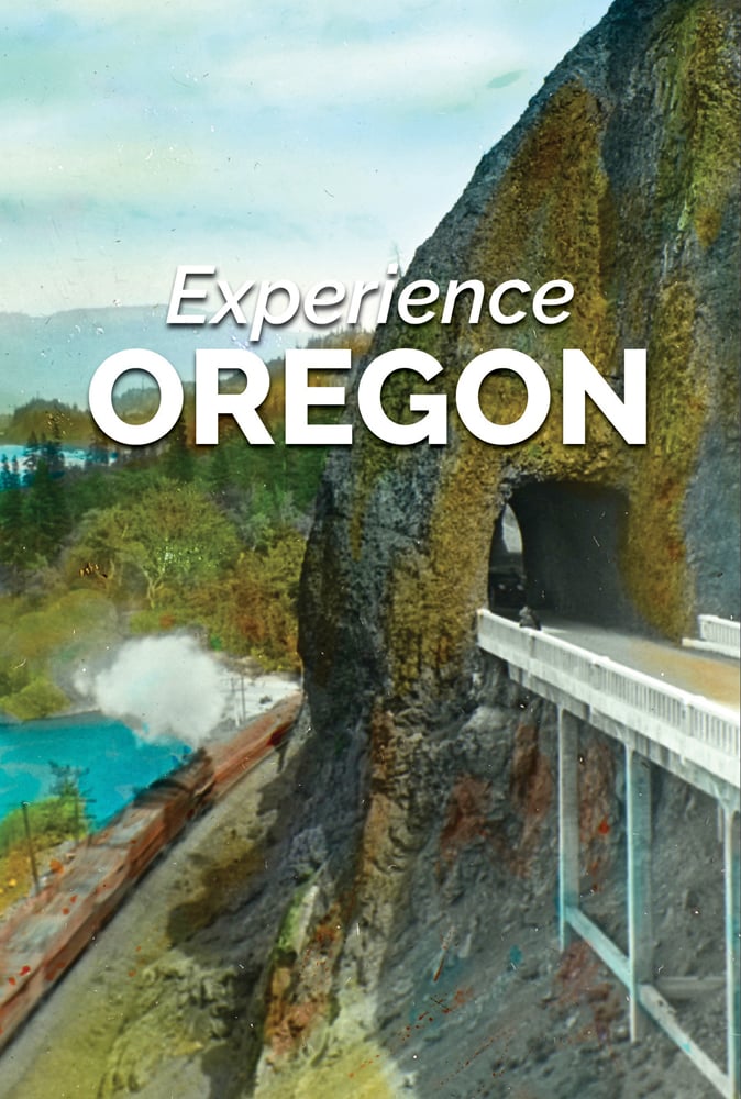 Rockface with archway for road to pass through with view below of steam train on tracks and Experience Oregon in white font