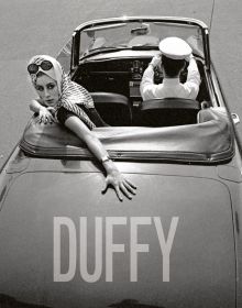 Fashion model in the back seat of convertible car driven by chauffer, on cover of 'Duffy', by ACC Art Books.