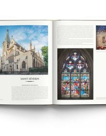 The atmospheric gothic interior of Sainte-Chapelle in Paris, stained glass windows with fleurs de lys ceiling decoration, on cover of 'Churches of Paris', by ACC Art Books.