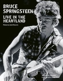 Bruce Springsteen wearing bandana, playing electric guitar on stage, on cover of 'Bruce Springsteen Live in the Heartland Photos by Janet Macoska', by ACC Art Books.
