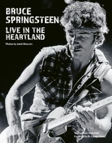 Book cover of Bruce Springsteen Live in the Heartland, featuring the singer songwriter wearing a bandana while playing electric guitar on stage,. Published by ACC Art Books.