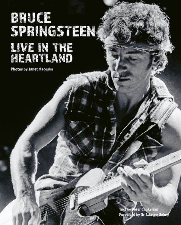 Book cover of Bruce Springsteen Live in the Heartland, featuring the singer songwriter wearing a bandana while playing electric guitar on stage,. Published by ACC Art Books.