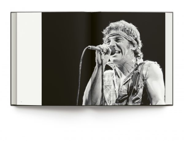 Book cover of Bruce Springsteen Live in the Heartland, featuring the singer songwriter wearing a bandana while playing electric guitar on stage,. Published by ACC Art Books.