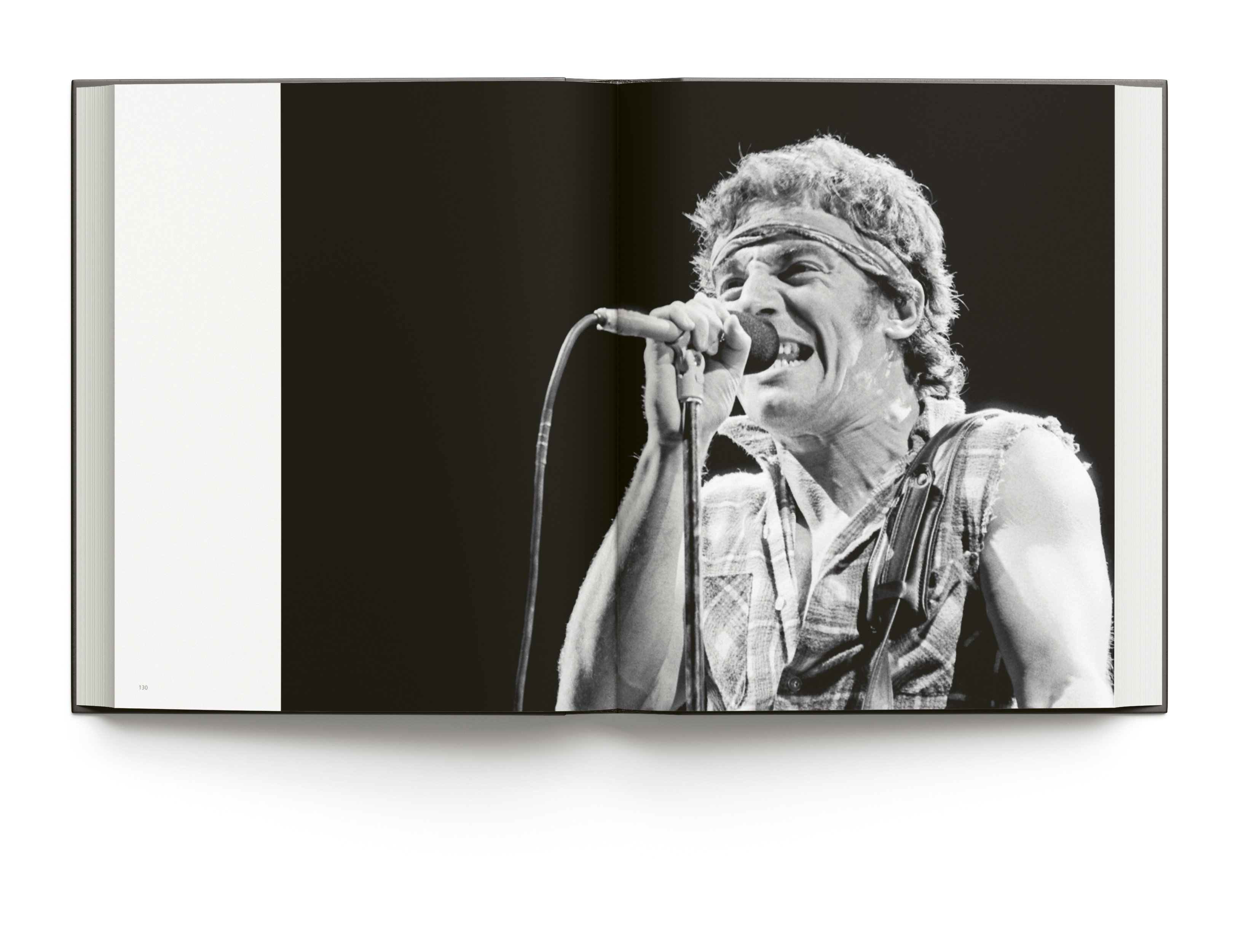 Book cover of Bruce Springsteen Live in the Heartland, featuring the singer songwriter wearing a bandana while playing electric guitar on stage,. Published by ACC Art Books.