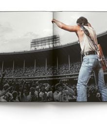 Bruce Springsteen wearing bandana, playing electric guitar on stage, on cover of 'Bruce Springsteen Live in the Heartland Photos by Janet Macoska', by ACC Art Books.