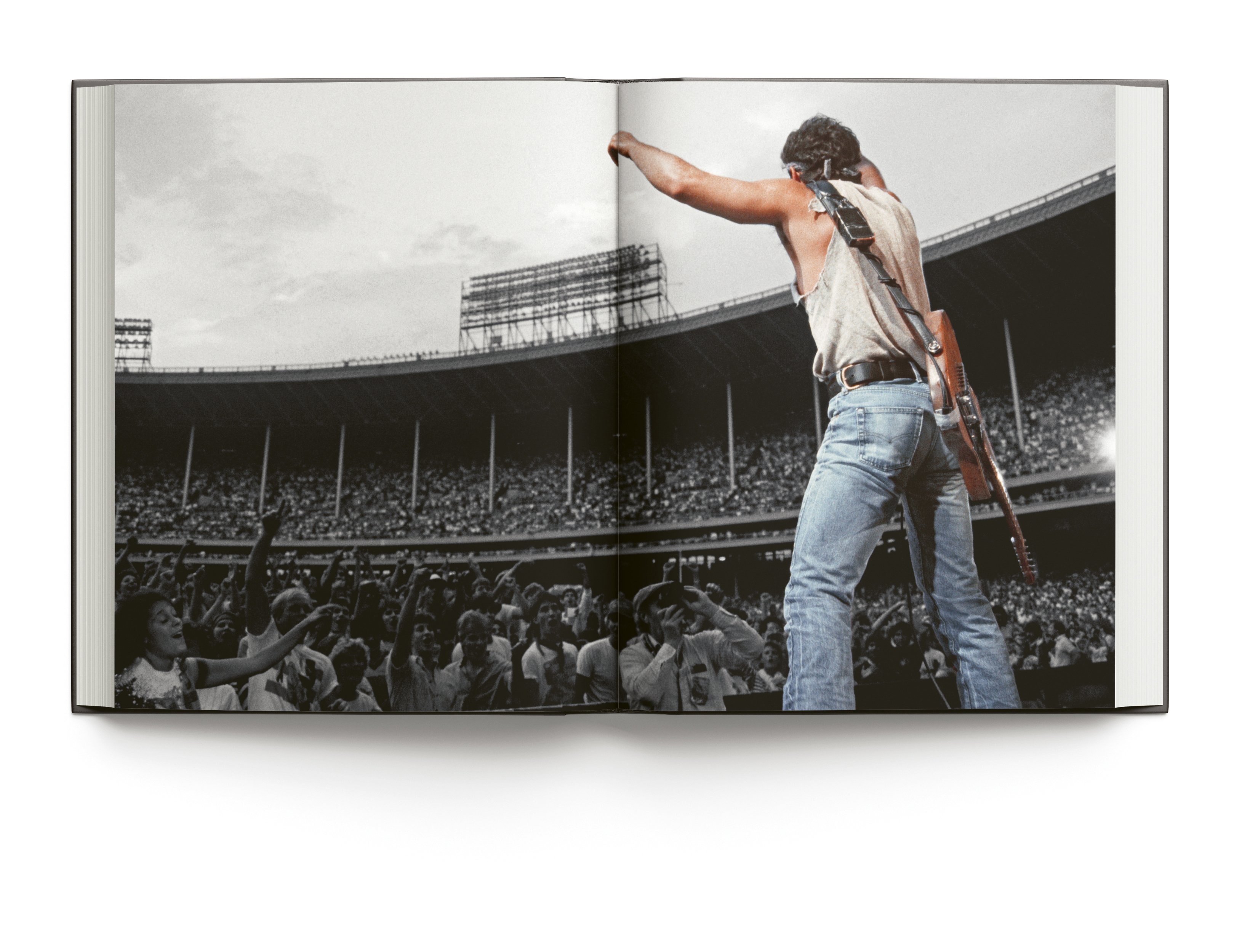 Book cover of Bruce Springsteen Live in the Heartland, featuring the singer songwriter wearing a bandana while playing electric guitar on stage,. Published by ACC Art Books.