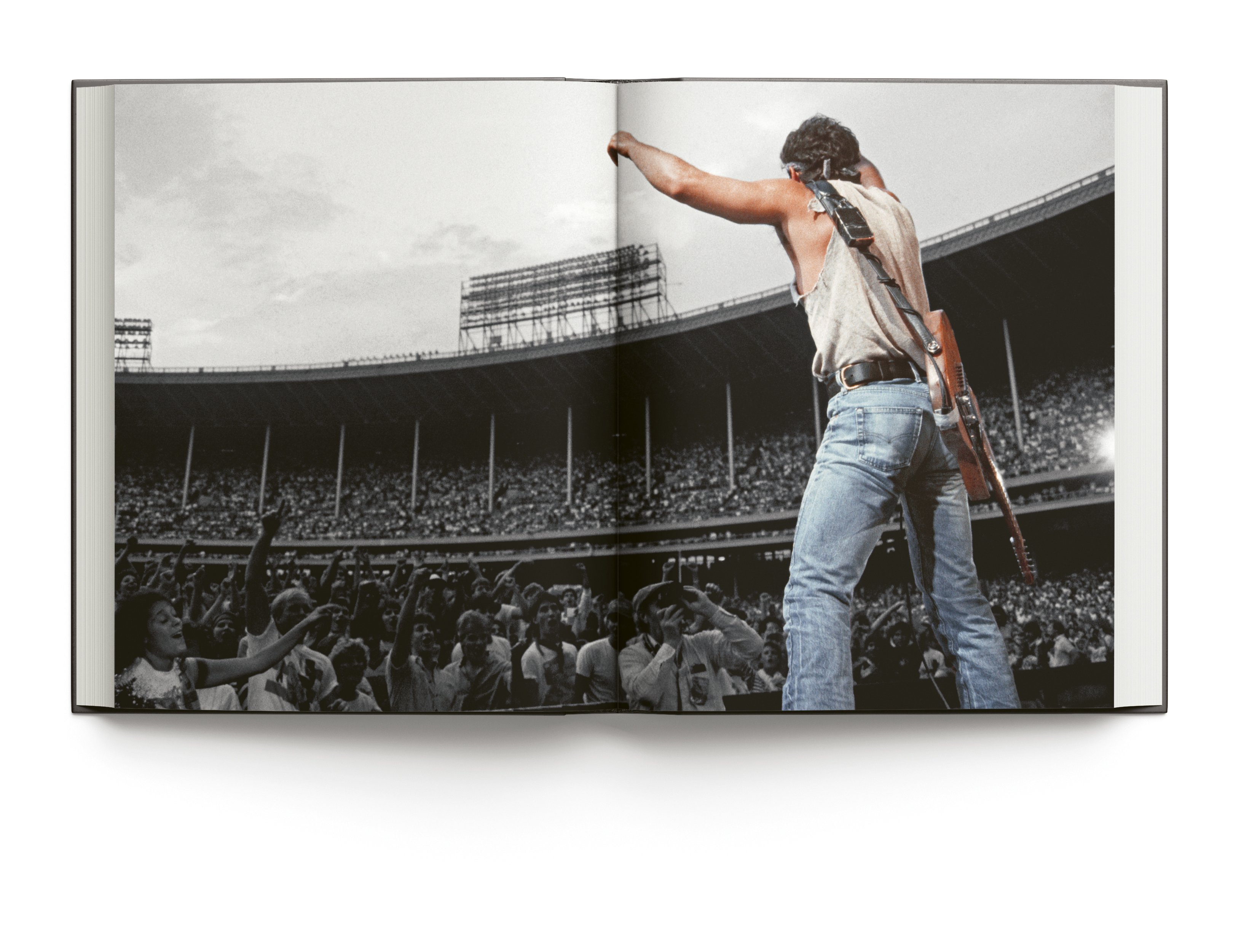 Bruce Springsteen wearing bandana, playing electric guitar on stage, on cover of 'Bruce Springsteen Live in the Heartland Photos by Janet Macoska', by ACC Art Books.