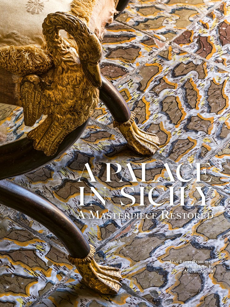 Aerial view colour photograph of a brown yellow and white pattern tiled floor with the edge of a seat featuring a gold swan with gold webbed feet and A Palace in Sicily A Masterpiece Restored in white