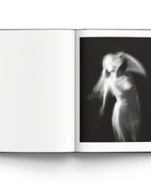 Black and white photograph of three quarter length blurred female nude in movement with Memory of Light in red, Steen Evald in white