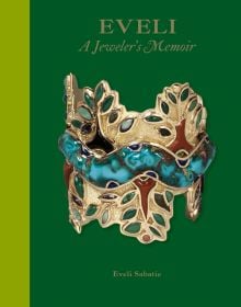 Large decorative gold bangle with green jewels, on green cover of EVELI A Jeweler’s Memoir.