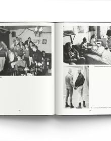 Young white male skinhead in black jacket, looking to his left, arms folded, 'SKINS', in black graffiti on wall behind, ACC Art Books.