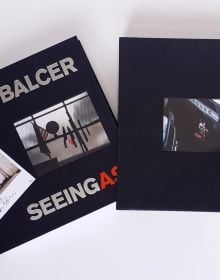 Book cover of Seeing As, René Balcer, with a row of knives and a machete, on a magnetic strip, with American flag and globe to left. Published by ACC Art Books.