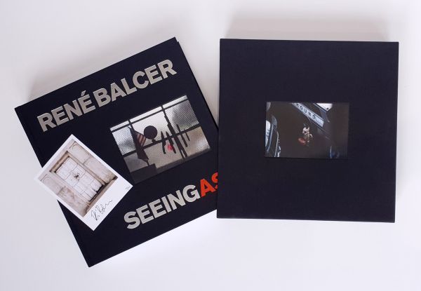Book cover of Seeing As, René Balcer, with a row of knives and a machete, on a magnetic strip, with American flag and globe to left. Published by ACC Art Books.