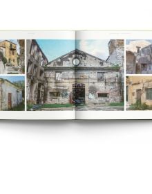 Sunny old village walkway to dark double doors of building, potted plants to right, on cover of 'Old Corfu' by ACC Art Books.