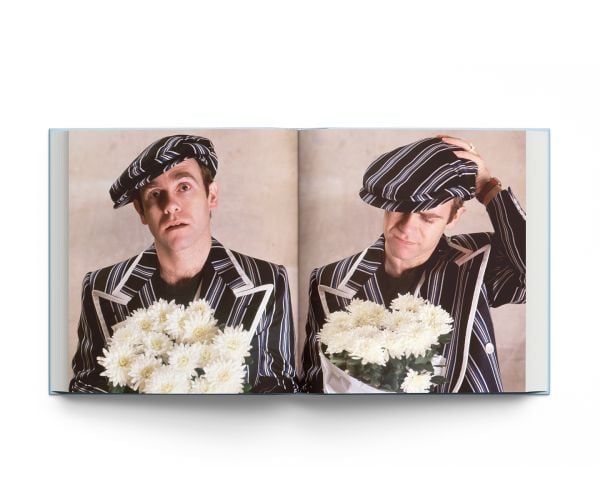 Book cover of Elton John: Icon; featuring the musician wearing a white suit and cowboy hat with blue stars. Published by ACC Art Books.