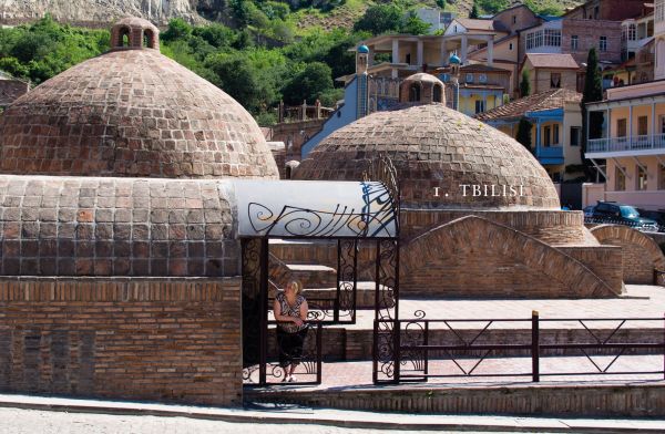 Traditional Georgian cotton tablecloth painted in various hues of blue, 'Tasting Georgia: A Food and Wine Journey in the Caucasus', in white font to pink banner above.