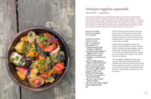 Traditional Georgian cotton tablecloth painted in various hues of blue, 'Tasting Georgia: A Food and Wine Journey in the Caucasus', in white font to pink banner above.