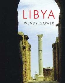 Dark archway in a Libyan city with tall column standing in the light, 'LIBYA', in red font above.