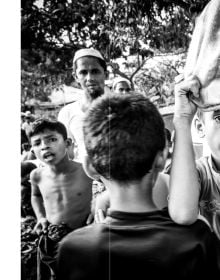 Landscape book cover of Edge of Hope, The Rohingya Refugee Camp at Cox's Bazar, featuring a group of children holding books, staring at viewer. Published by Pallas Athene.