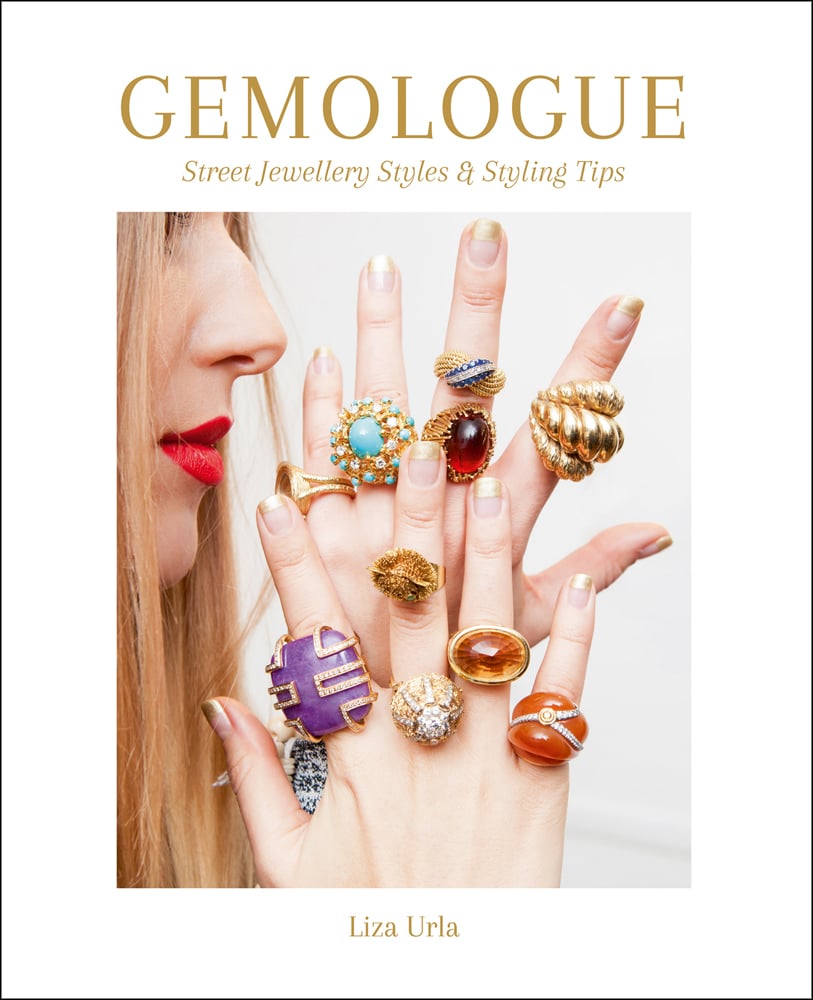 Model in red lipstick holding up ring covered fingers, on white cover of 'Gemologue Street Jewellery Styles & Styling Tips', by ACC Art Books.