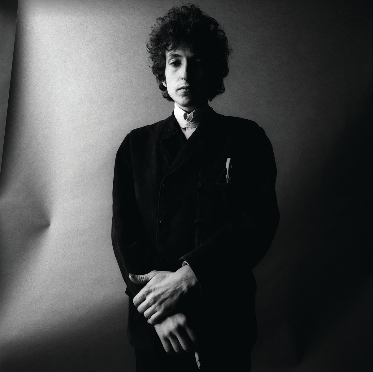 Sepia head and shoulder shot of Bob Dylan in a white scarf looking into the camera with Dylan By Schatzberg in black capital letters