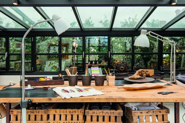 Book cover of Creative Spaces for Creative Ideas, with an artist sitting in wooden studio, with tree hammock in foreground. Published by Images Publishing.