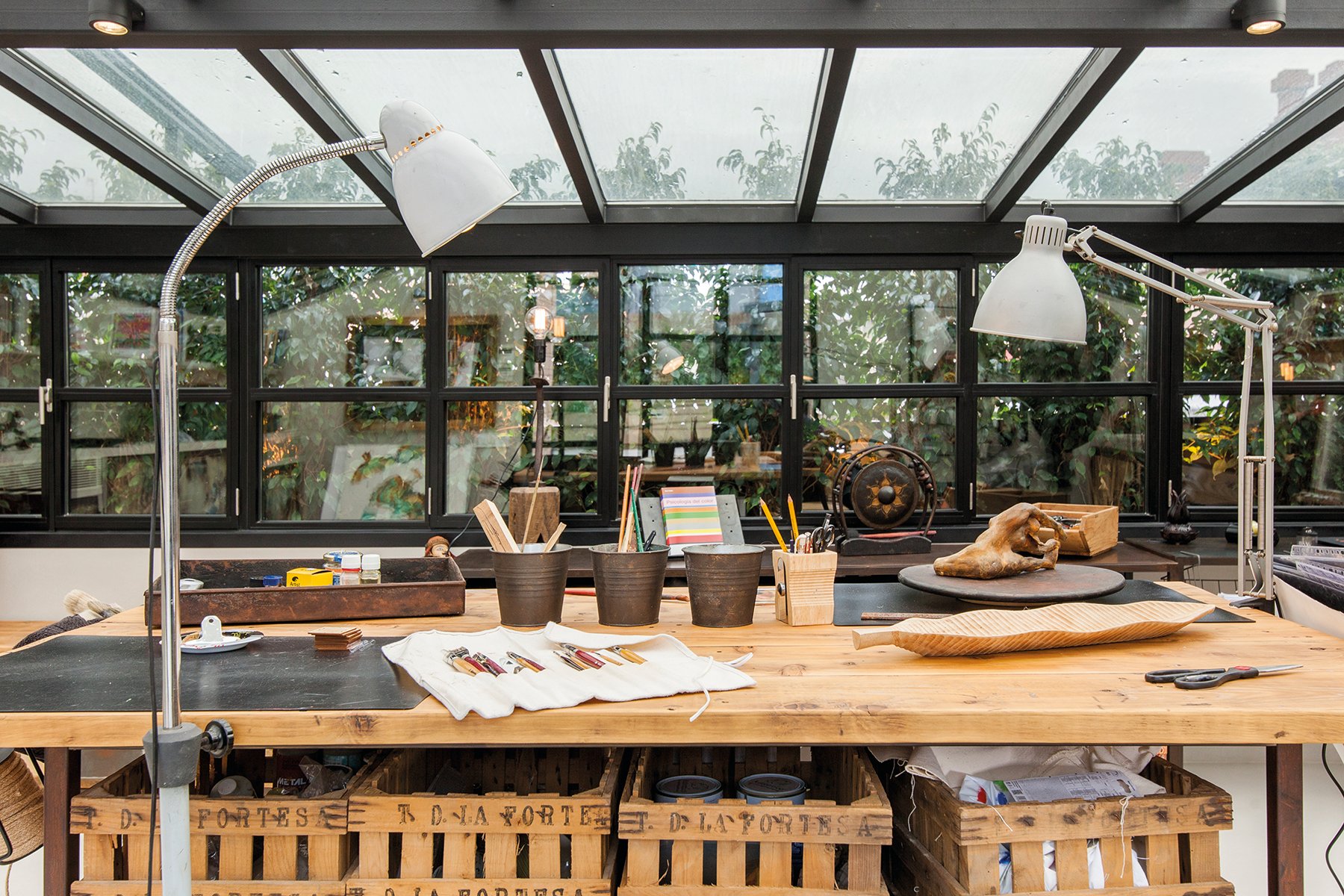 Artist sitting in wood studio, tree hammock in foreground, on green cover, Creative Spaces for Creative Ideas in white font above.