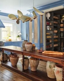 Kitchen interior space, blue fittings, wooden table, copper pan on hob, Classic Kitchens for Modern Living in white font to lower right corner